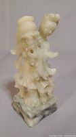 Full view of the white jade carving showing front and right side of the woman holding an upturned flower pot.