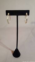 Front view of both sterling silver hoop earrings displayed on black stand, showing their size and polished finish.