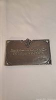 Full view of the brass plaque showing embossed quotation and decorative top center detailing.