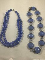 Both blue bead necklaces shown side by side on flat surface