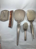 Full view of the 5-piece vintage BIRKS sterling silver vanity set including dish, comb with case, hand mirror, and two brushes.