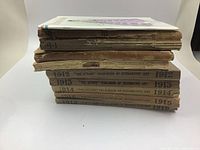 Side view of stack of books showing spines, titles, and condition with visible wear and tear.