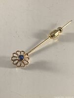 Another close-up angle emphasizing the delicate gold flower design and the gemstone center.