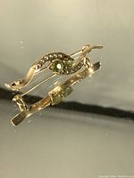 Close side angle view showing S-curve gold frame, bezel settings, and seed pearls along interior curve.