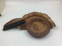 Three-piece set of wooden dustpan, round tray, and small brush on white background.