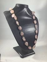 Full view of the long necklace displayed on black bust stand, showing the distribution of rose quartz stones along the chain.