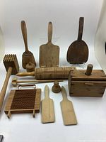 Full lot of vintage wooden kitchen tools arranged upright and flat on surface, showing variety of shapes and sizes.