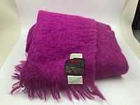 Photo of folded fuchsia mohair blanket showing color, texture, and fringed edges
