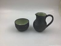 Front view of cup and jug side by side showing shape and texture