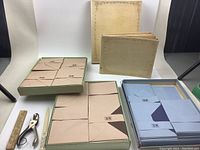 Photo shows 8 vintage stationery items: three boxes of envelopes in beige and blue, two cream cover booklets, a wooden ruler, and metal hole punch on a white background.