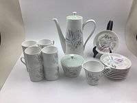 Full set displaying teapot, six tea cups, six saucers, sugar bowl with lid and creamer. White porcelain with delicate floral pink and green pattern.