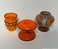 Front view of three Mid-Century Modern art glass vases showing different shapes and decoration styles in orange and blue tones.