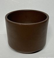 Front view of brown ceramic planter showing smooth cylindrical shape and even color.