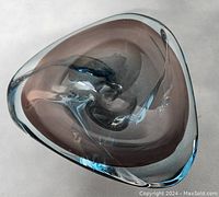 View from the top showing the curling ribbon-like design inside the triangular ashtray in clear blue and purple hues.