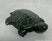 Natural jade turtle figurine shown from angled top view highlighting shell pattern and carving details.