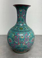 Front view of the vase showing detailed turquoise and pink enamel floral and geometric patterns.