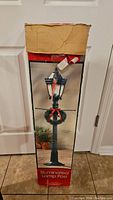 Box of Christmas illuminated lamp post with image showing the product and packaging details. Box is slightly worn at top.