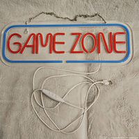 Full view of the Game Zone light-up sign showing red illuminated lettering and blue border with attached USB cable and hanging chain.