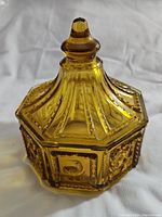 Amber-colored Imperial Glass candy dish with detailed raised decoration, lid attached, showing intact condition.