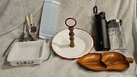 Various kitchen utensils and serveware including knives, baking dish, serving trays, water bottles.