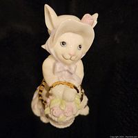 Front view of bunny figurine showing bonnet, bow, and basket of flowers