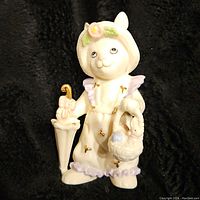 Front view of the Lenox bunny figurine showing bonnet, overalls with gold bows, umbrella and basket with eggs.