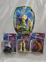 Photo shows five Disney character figurines all new in their original packaging including Tinker Bell, Ursula, Cruella de Vil, and Beast.