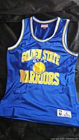 Front view of blue Golden State Warriors basketball jersey showing team name and logo.