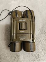 Front view showing Tasco branding, 10x25 magnification and optical specifications.