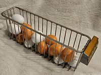 Side angle view of rectangular metal wire basket filled with white and brown faux eggs.