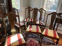 Front angle showing five chairs with striped red and cream seats and mahogany backs with curved top rail.