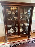 Front view of the mahogany wood cabinet showing glass mullion doors, carved columns and claw feet