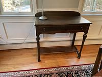 Front view of mahogany silverware chest with single drawer, showing turned legs, drawer handles, lower shelf and backboard.