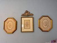 Frontal photo showing three framed wall art pieces and a cherub accent above the center print
