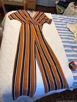 Full length view of the pant jumper laid on a bed showing its overall cut and colors.