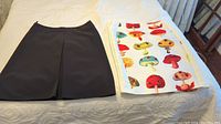 Photo of two skirts laid flat on a bed, one black and one with mushroom print.