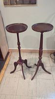 Pair of vintage mahogany painted plant stands, showing full height and tripod legs.