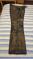 Photo of the full length of one pant leg, showing leather material and hems.