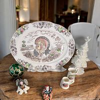 Turkey platter with detailed turkey scene and ornate border, placed on wood table with other lot items in background