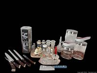 Photo showing the assortment of vintage mid-century culinary items including knives, salt and pepper shakers, lidded tins, glass containers with spoons, and other kitchen utensils.