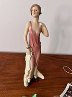 Front view of Goebel porcelain figurine of woman in pink dress holding white cloth.