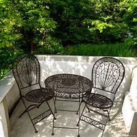 Photo of the full set placed outdoors showing two chairs and one table with greenery background.