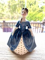 Front view of Royal Doulton figurine showing the woman in a blue dress with white and gold underskirt, posed gracefully