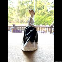 Side view of the Royal Doulton Lisa figurine showing the white polka dot bodice and flowing blue skirt with white scalloped edge.