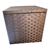 Front view of cube-shaped ottoman with woven basketlike exterior and lid on.