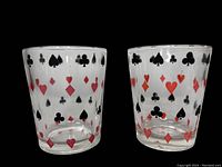 Two clear glasses side by side, showing full playing card suit pattern in red and black colors all around