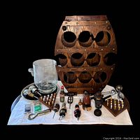 Full display of lot items including wooden wine rack, ice bucket, bar tools, stoppers, and chess sets.