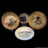Set of four handcrafted vintage decorative ceramic plates with rural and domestic scenes, displayed together