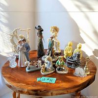 Overview photo showing the 14 vintage figurines and decor pieces arranged on a wooden round table in natural light.