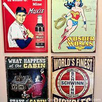 Four metal hanging advertising signs laid out together showing the full set of designs featuring Moxie, Wonder Woman, Cabin and Schwinn logos.